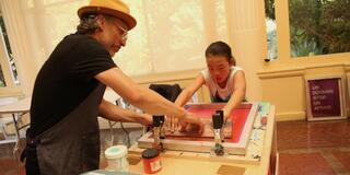 Sergio De La Torre works on art with a young girl