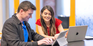 Two USF students working together on their laptops