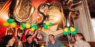 Alumni laughing and holding USF balloons