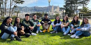A group of students sit on the lawn on Lone Mountain.