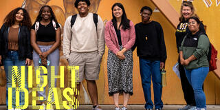 group of McCarthy center students/faculty standing and smiling in front of a wall