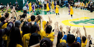 Students raising their hands at a basketball game