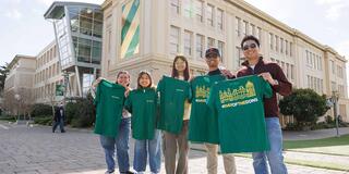 Student holding shirts and smiling