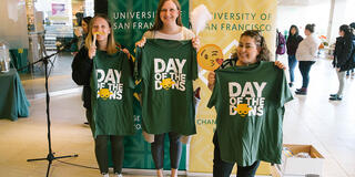 Three people holding t-shirts