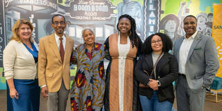 group of faculty stand in front of mural