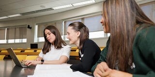 Three USF law students in a lecture room working on a project
