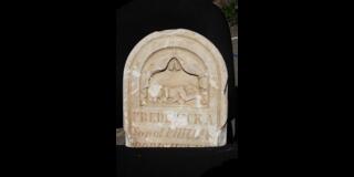 Gravestone with a child and a lamb carving and partially legible inscription including the name “Frederick A.”