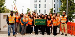 Students holding a USF banner wearing construction vests