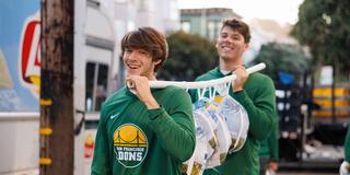Two USF students carrying donated turkeys and smiling