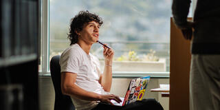 student sits in library with laptop on lap
