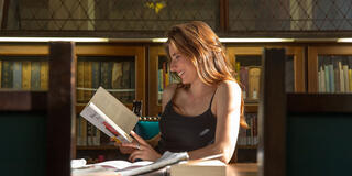 Woman in library smiling and reading a book
