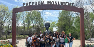 Group of USF Equal Justice Institute students in Alabama standing under a "Freedom Monument" sign