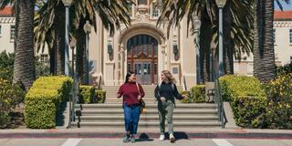 two students walking in front of the Lone Mountain building on USF's Hilltop campus