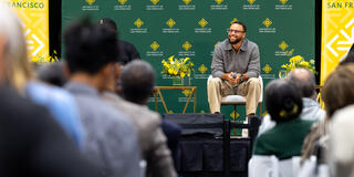 Steph Curry sits on stage and smiles at crowd at the Silk Speaker Series event