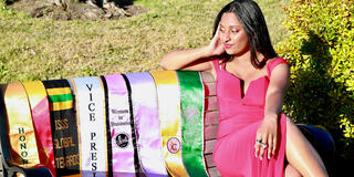 Tanya Sanjay sitting on a bench next to her eight graduation stoles