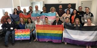 Group of people standing in a classroom holding flags 