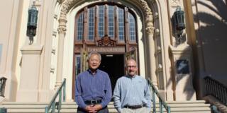 Two alumni stand in front of Lone Mountain