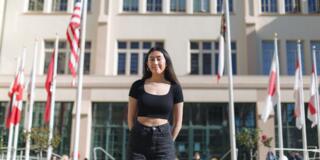 Student stands in front of flags on Lone Mountain