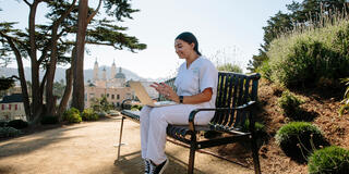 Elizabeth Elnemr studying out outside table in her nursing uniform