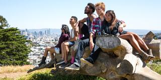 USF students sitting outside with a view of downtown San Francisco behind them.