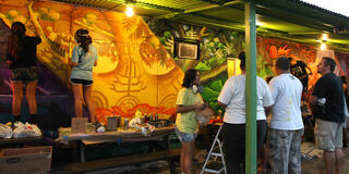 USF artist Estria Miyashiro '92 and students paint a mural depicting Hawaiian culture and lore