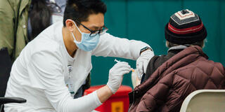 Norman Feng gives vaccination to patient.