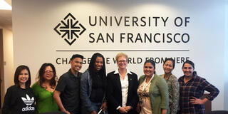 Members of the MSN Cohort for 2017 standing in front of a USF logo with Dean Maggie Baker