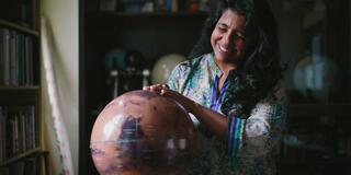 Physics Professor Aparna Venkatesan holds a globe