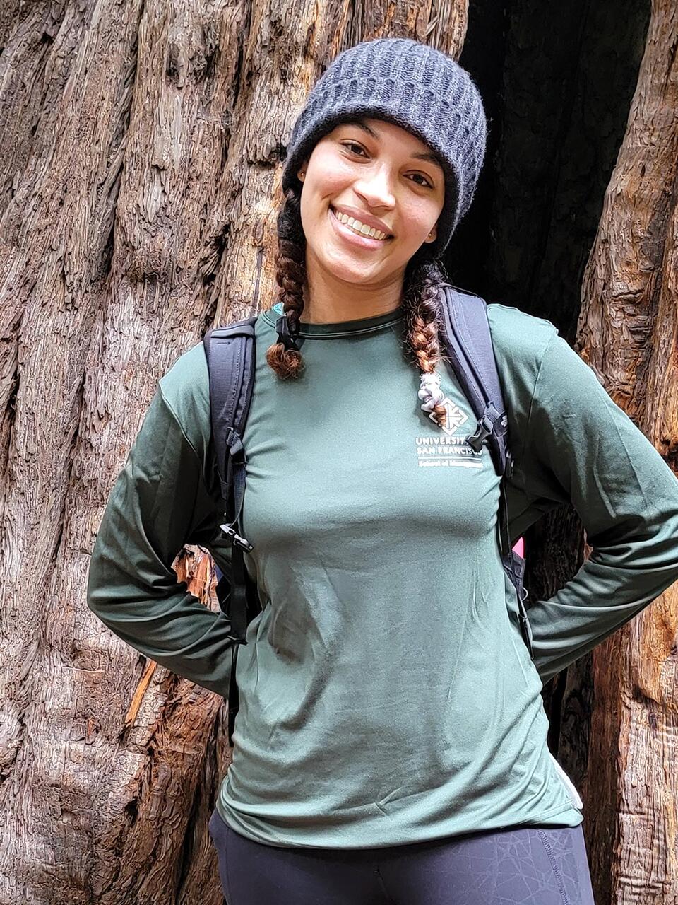 Student poses in front of a redwood tree.