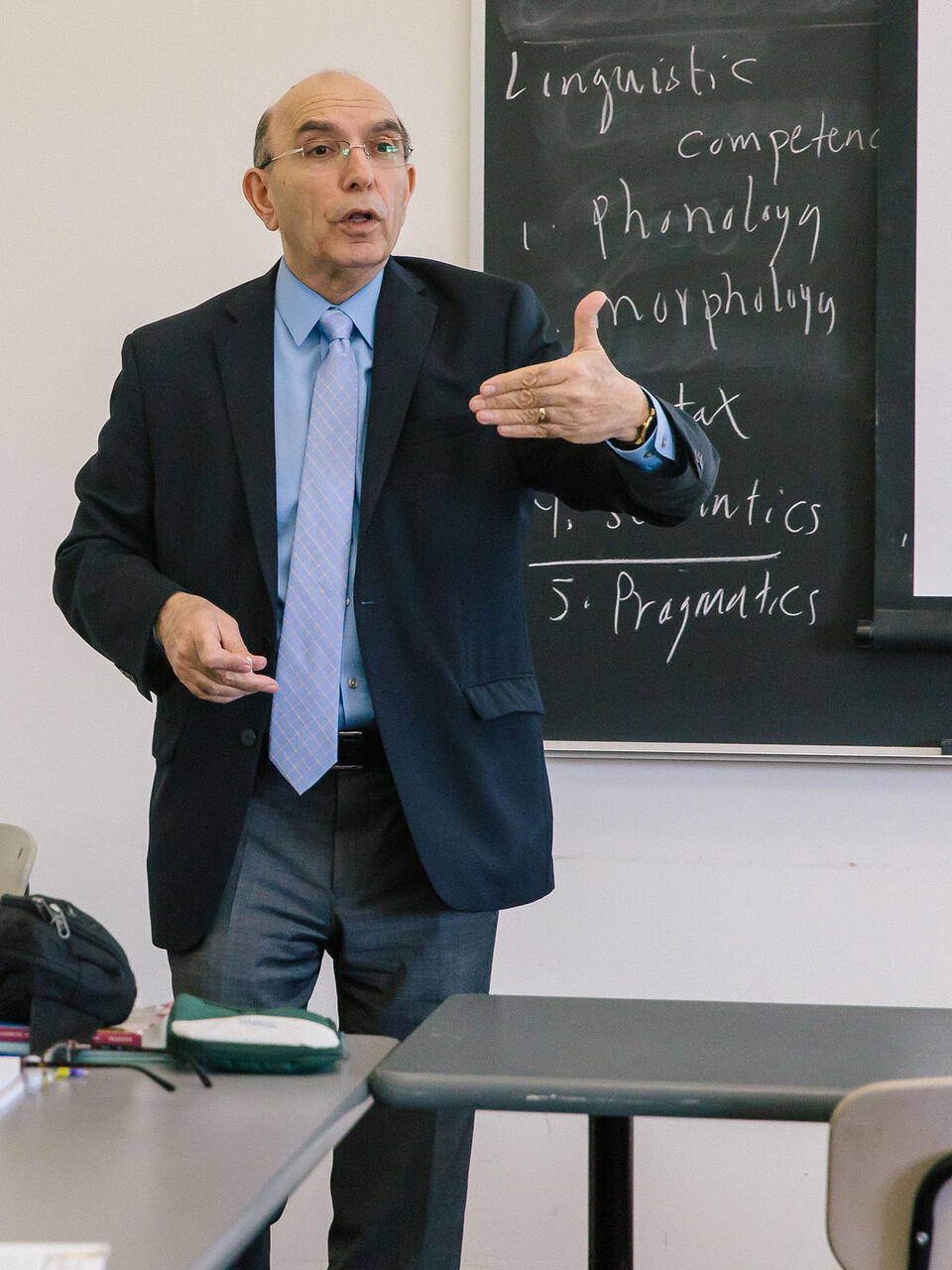 Teacher lectures from the front of a classroom.