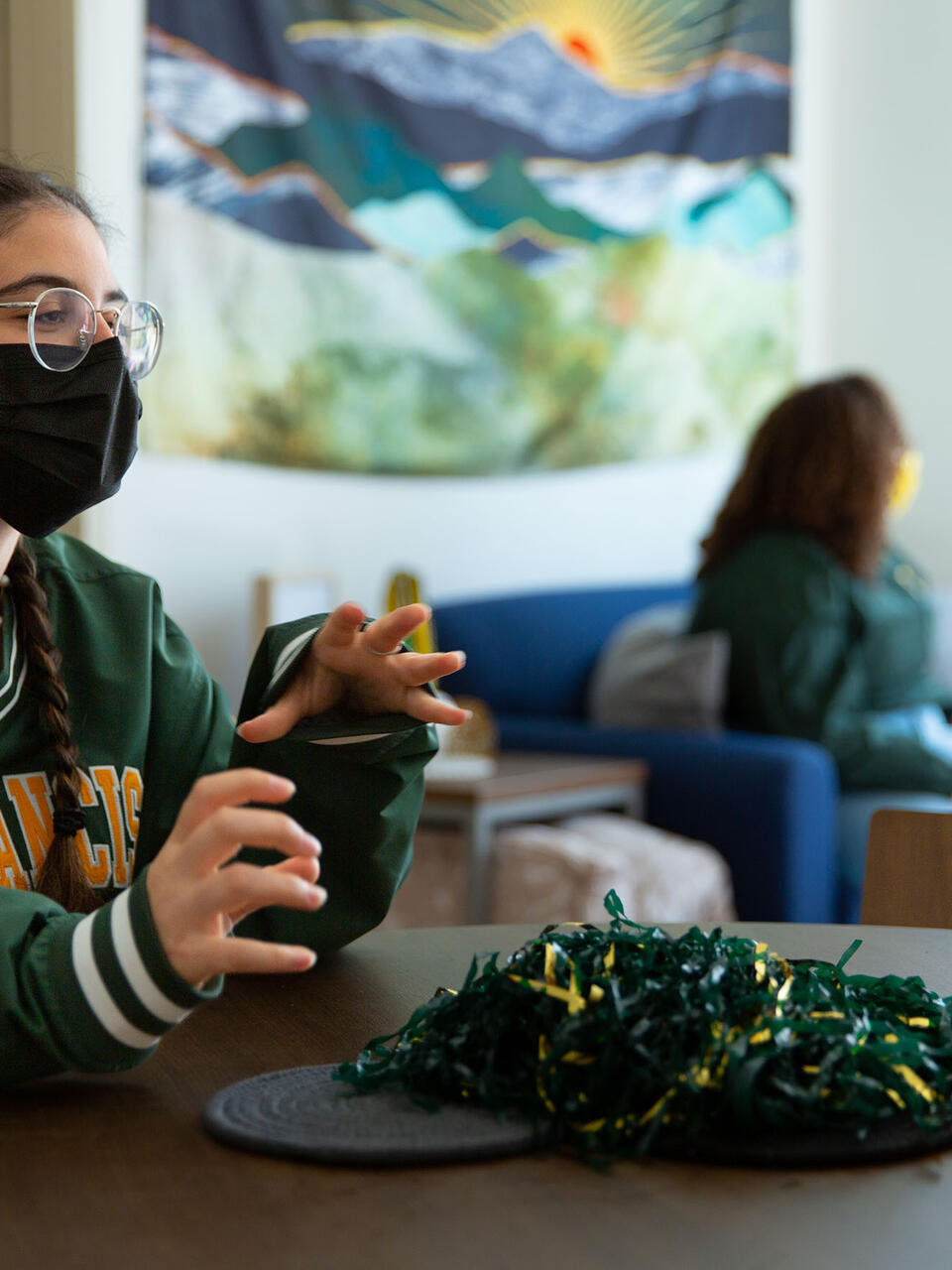 Student in a USF sweatshirt talks at a table in a common area