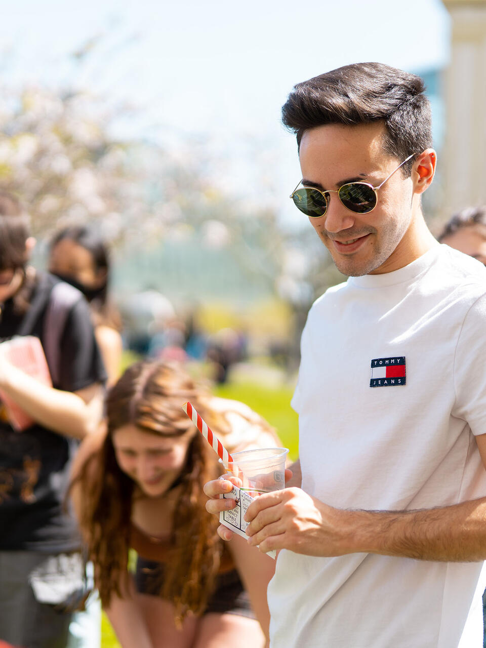 Students examine information on tables at an event on the lawn.