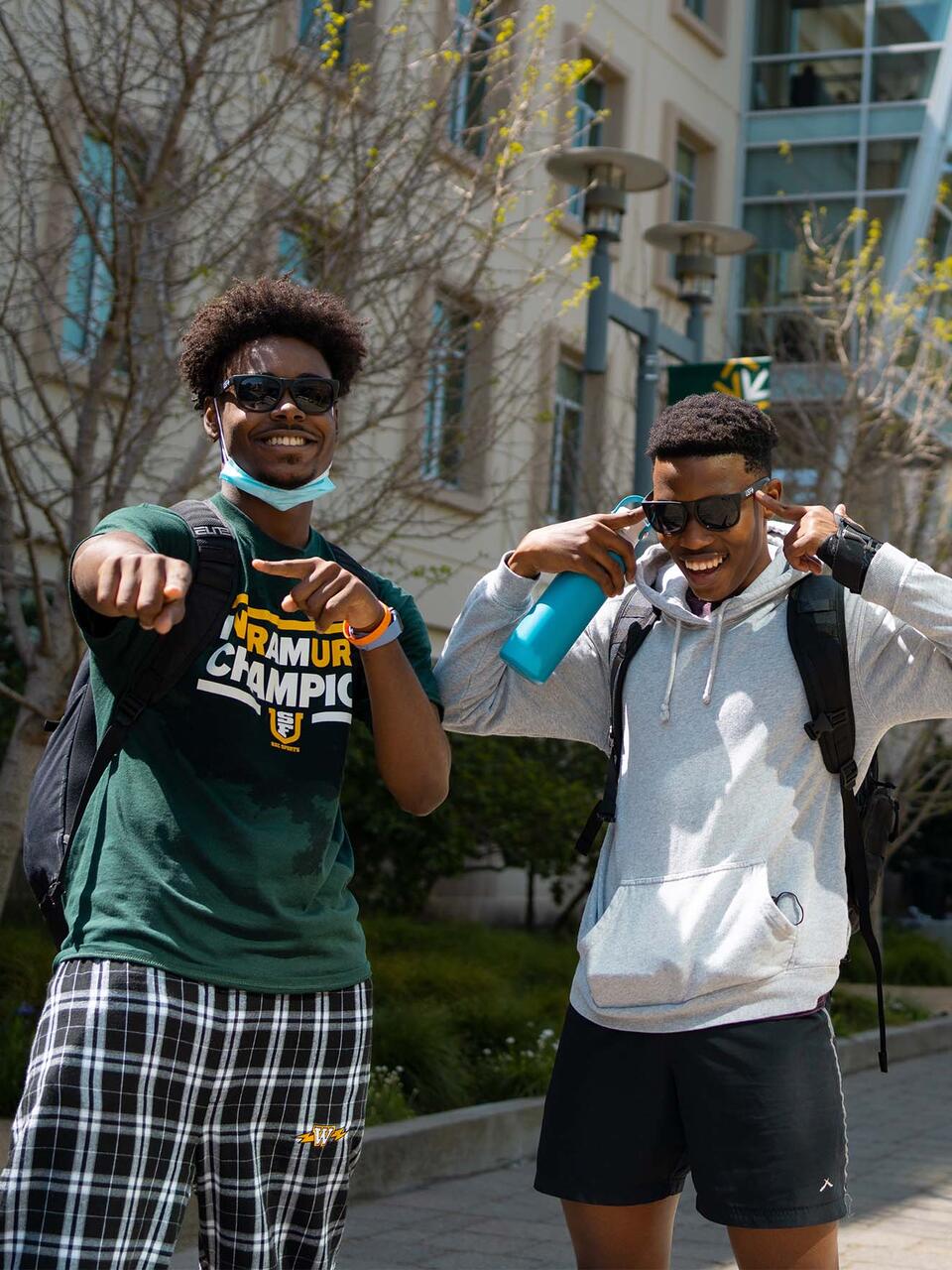 Two students laugh and point at the camera on USF campus.