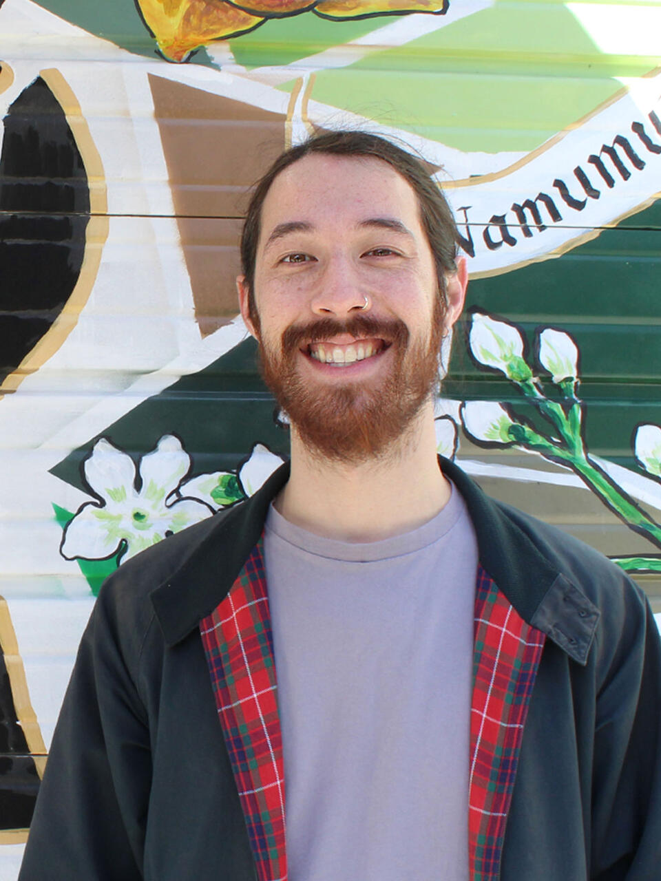 David Woo in front of a mural that reads SOMA