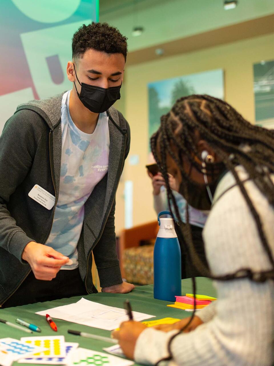 Student wearing a mask gathers materials off a table at jobs fest.