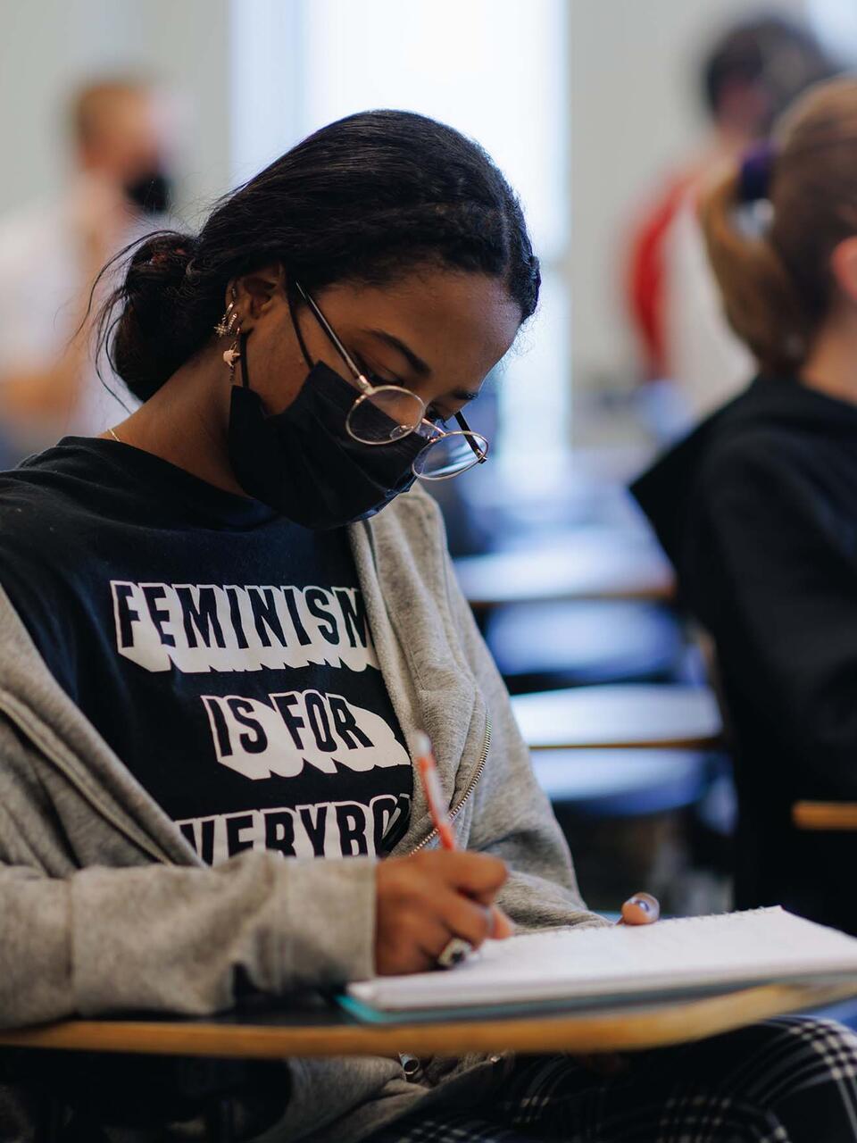 Student diligently writes in a notebook in class