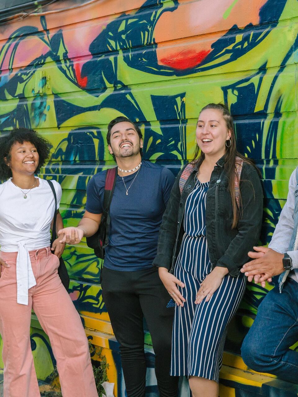 Students stand in front of wall with graffiti