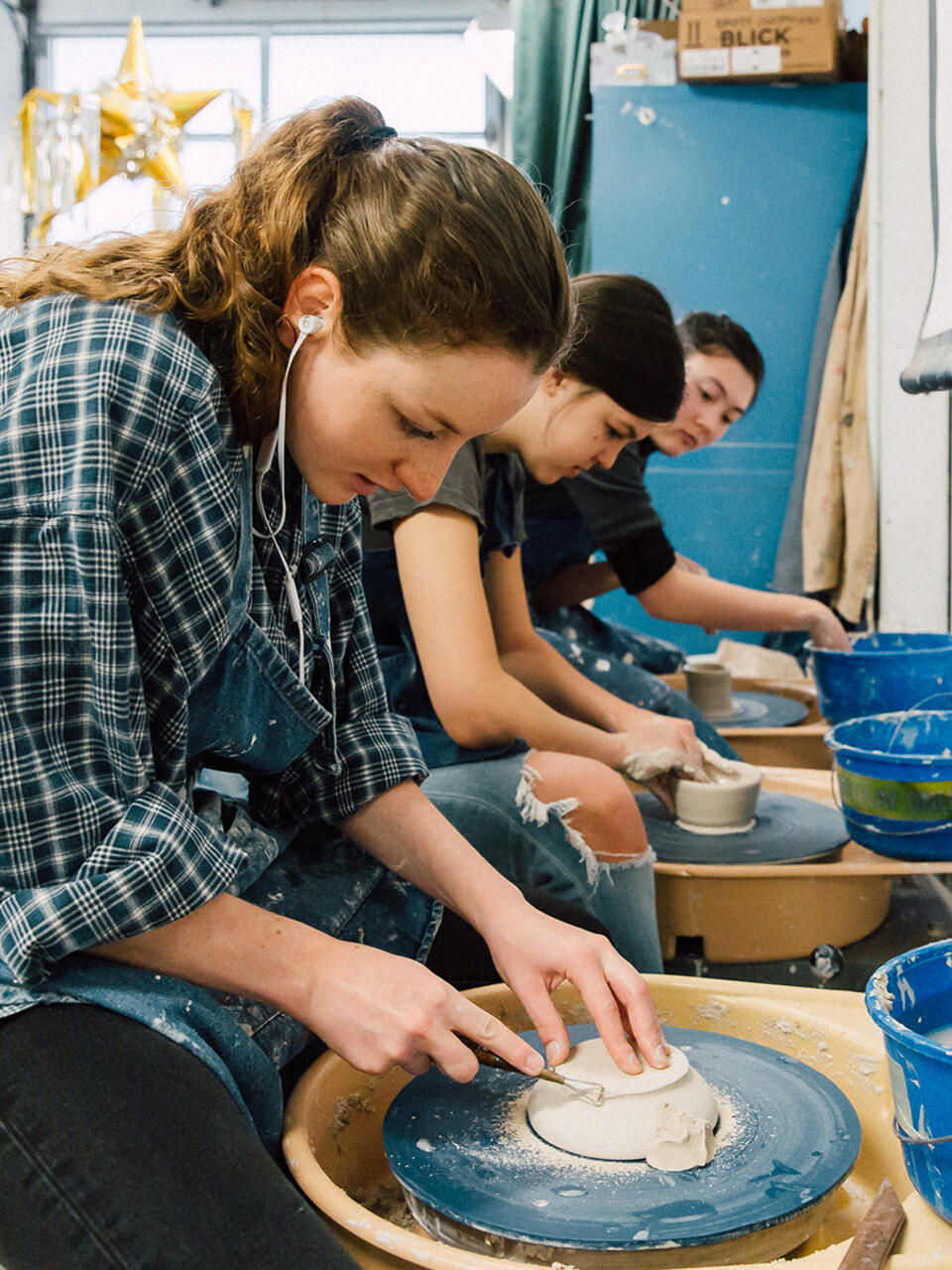 students creating ceramic pieces with wheel throwing machine
