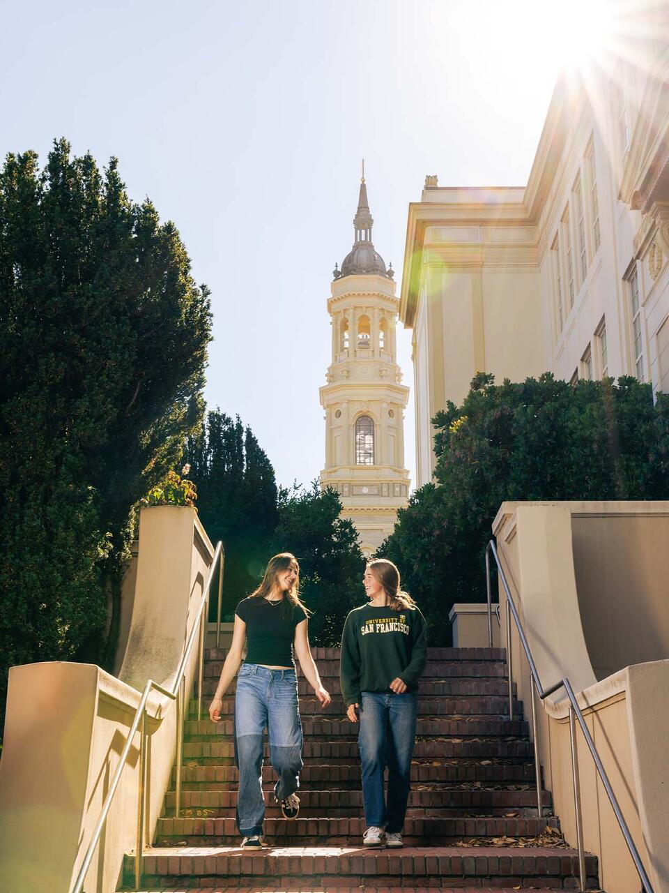 Two students walking down stairs with the church in the background